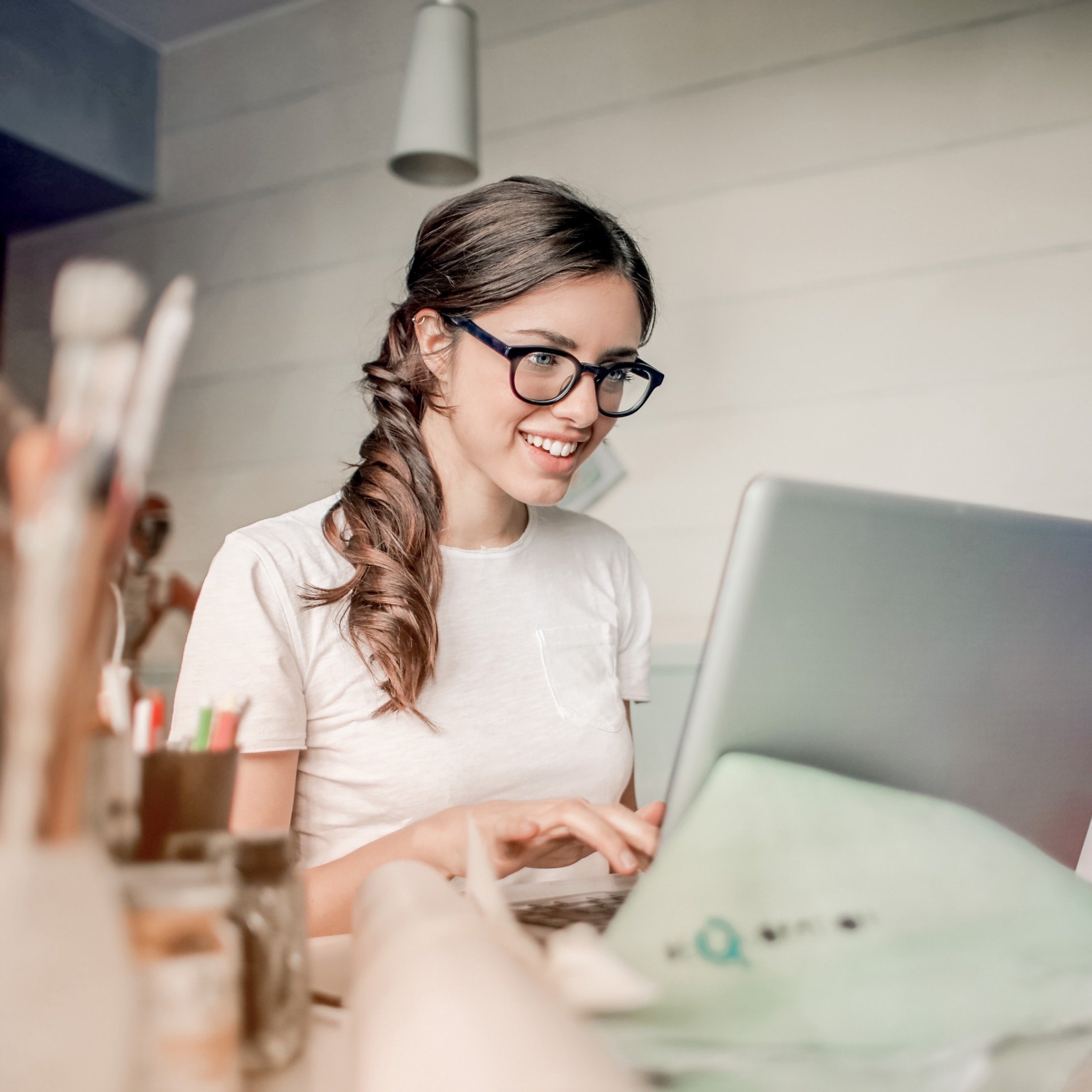 a lady with glasses on sitting looking at her desk in her home office