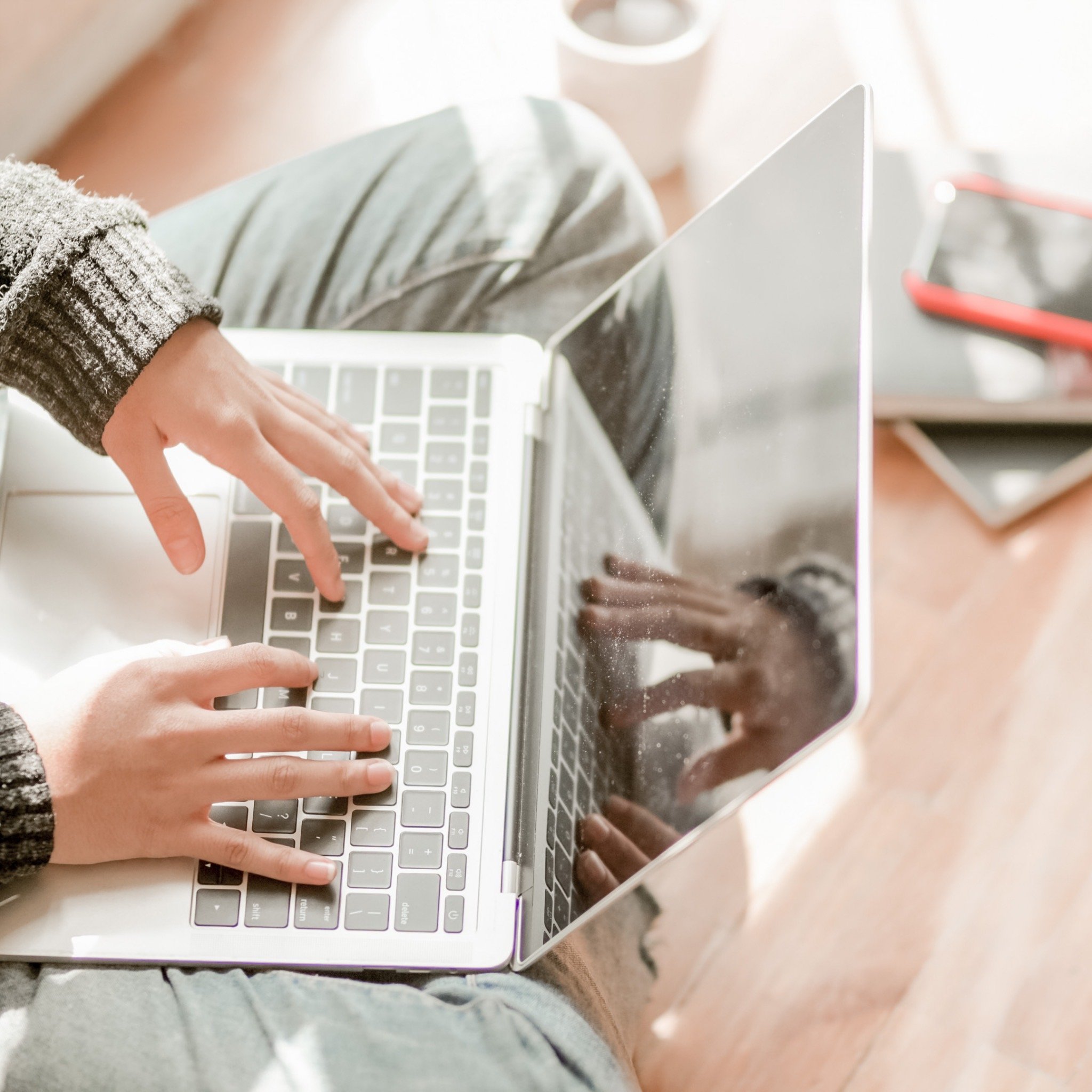 a person sitting crossed legged with a lap top on their lap working from home