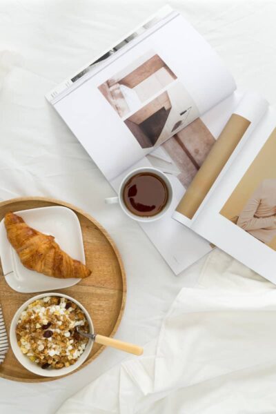 a cosy morning routine set up on the bed with breakfast and a magazine