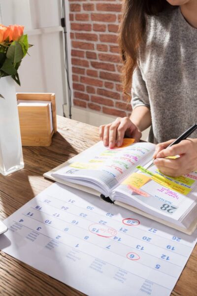 a lady sitting at a table organising her week in a planner