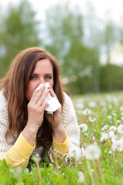 a lady blowing her nose into a tissue trying to manage her hay fever