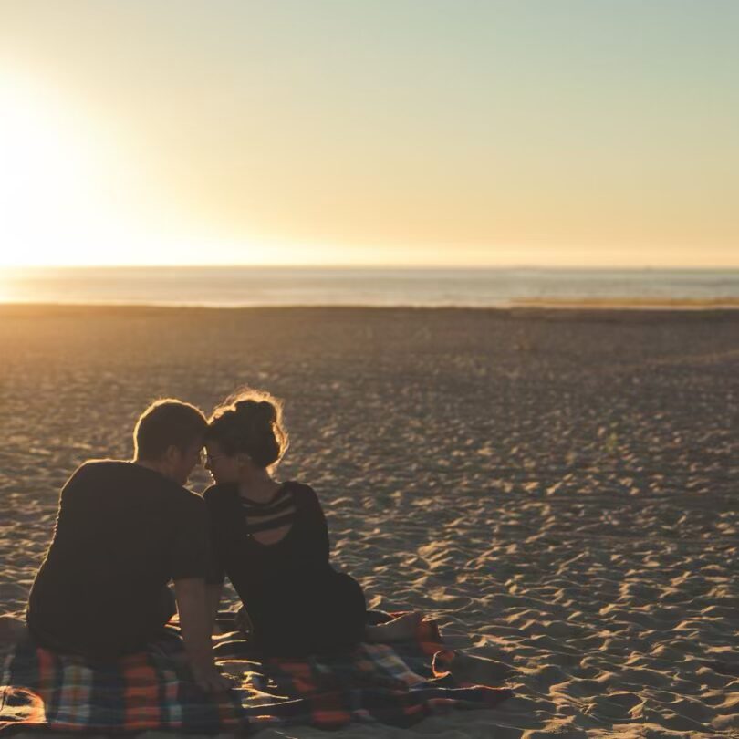 a man and woman sitting on a beach